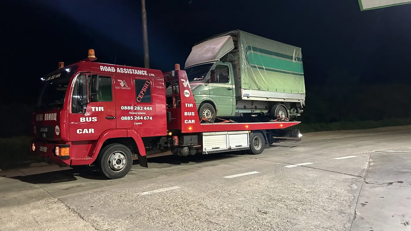 Камионът на Road Assistance нощем на бензиностанция, с качен товарен бус
